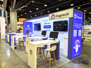 DiagnoCat's trade show booth with promotional displays for the 'Best New Imaging Product', encouraging social media engagement at the PDC show.